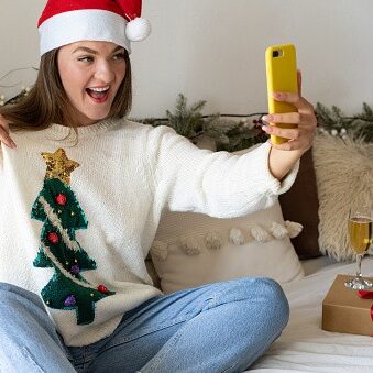 Girl showing her Christmas sweater through a video call to friends. Quarantine. Self-isolation. Coronavirus 2020.